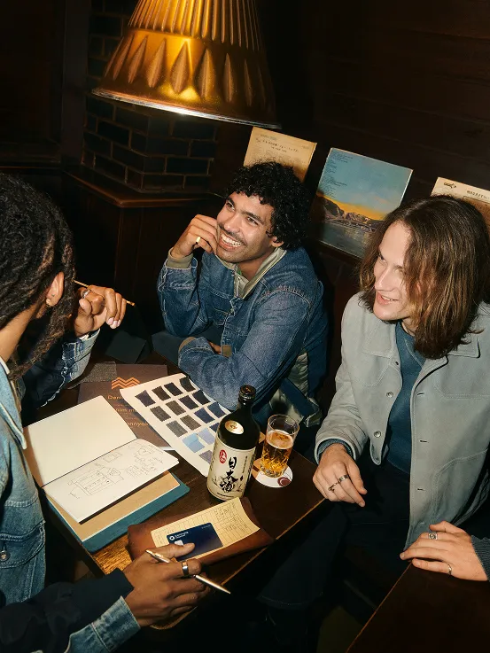 Three men sitting at a table at a dark lit restaurant. 
