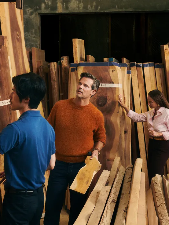 2 Men and 1 woman looking deciding on different slabs of wood.