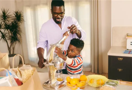 Father and son squeezing oranges in a kitchen